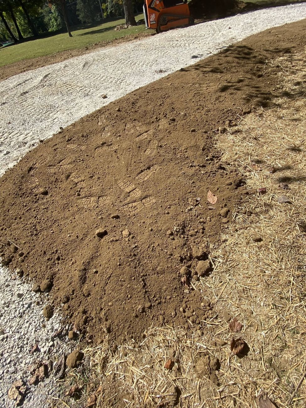 Fresh soil graded away from a foundation after drainage work