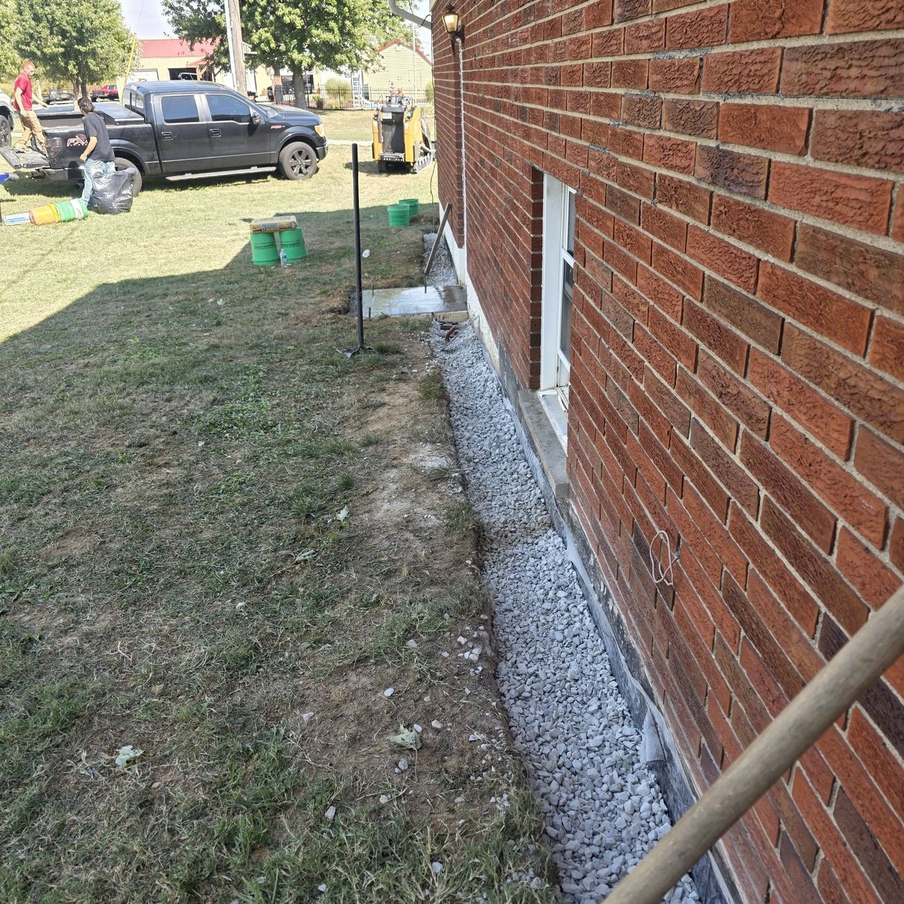 A finished gravel French drain running along a brick foundation