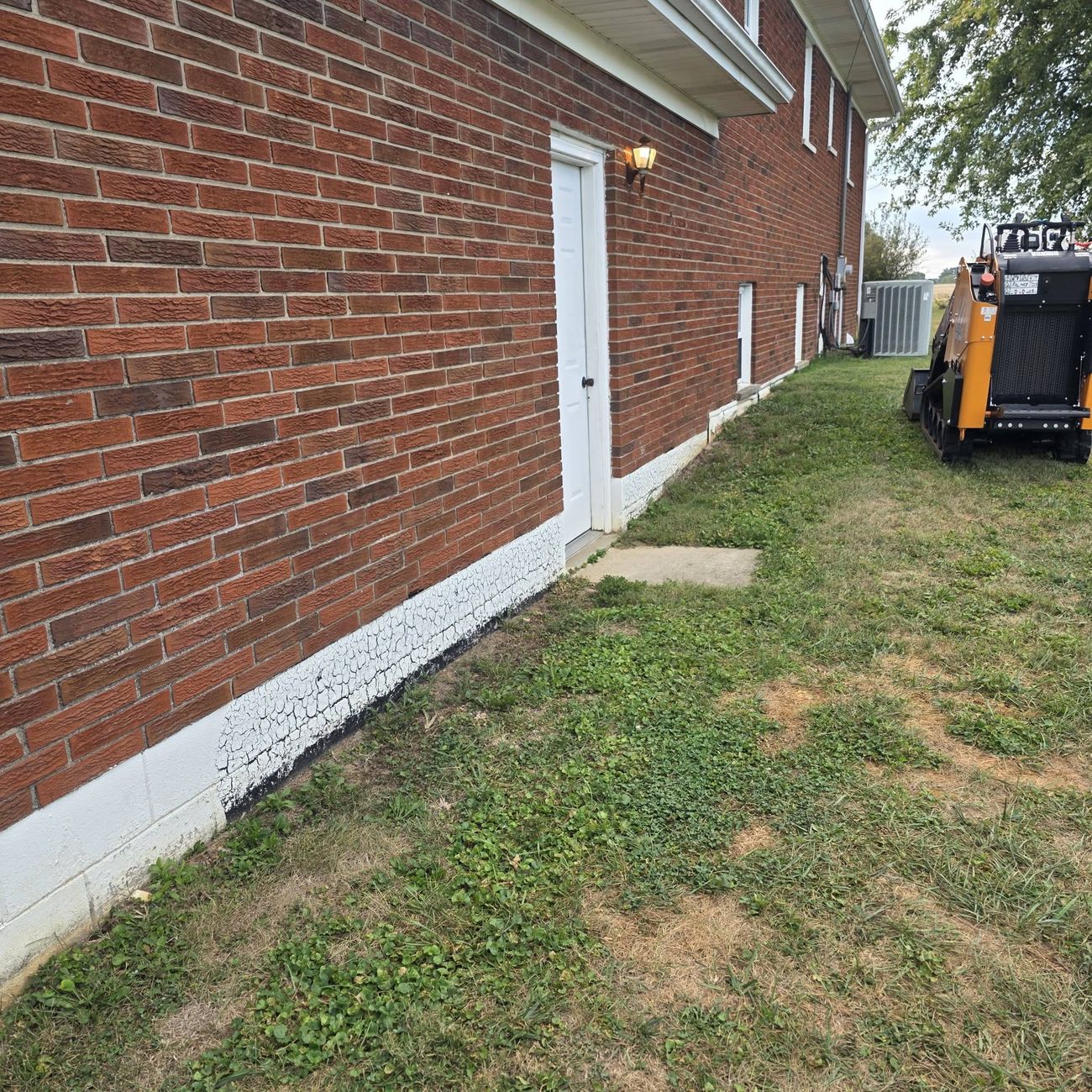 A gravel French drain line running along a brick foundation wall