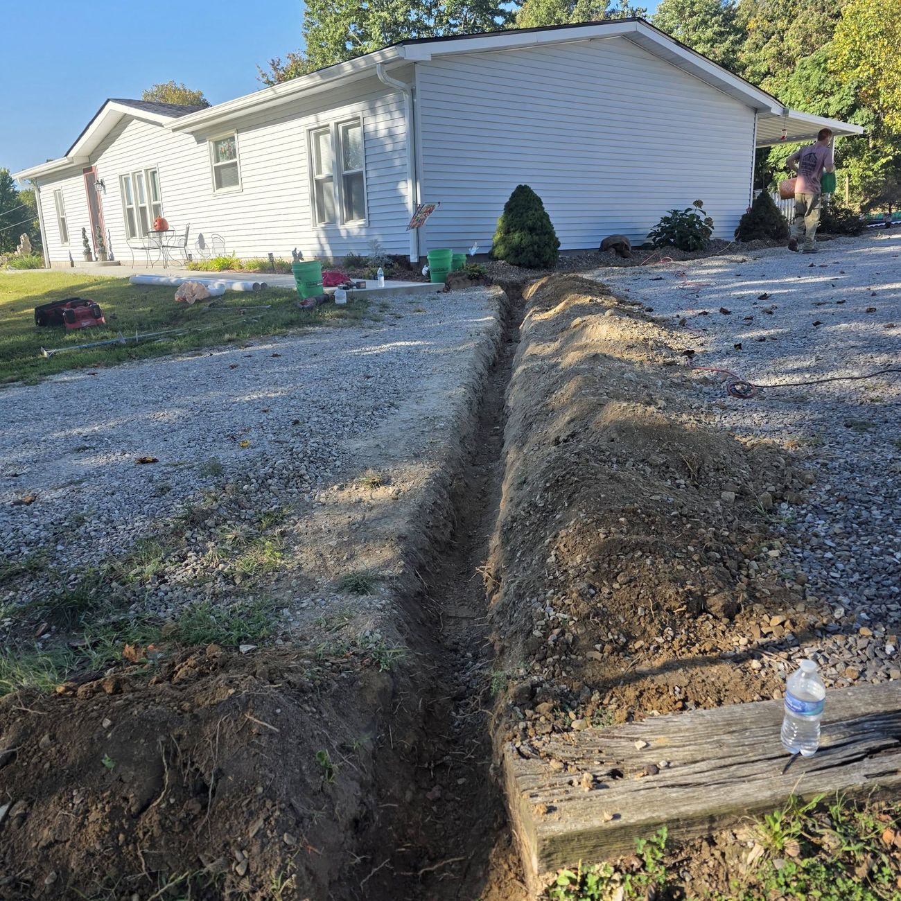 A trench cut alongside a house for a new drainage line