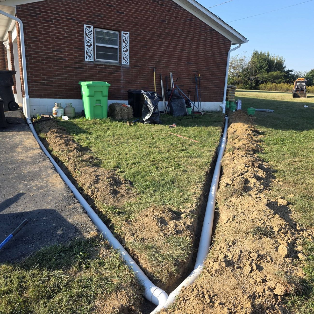 Drain pipe laid in an open trench beside a brick house